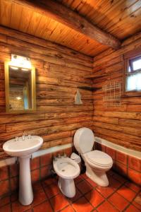 a bathroom with a toilet and a sink in a log cabin at Del Milagro Cabañas & Posada in Villa General Belgrano
