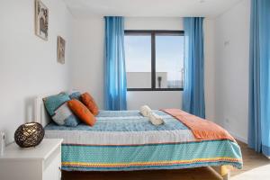 a bedroom with a bed with blue curtains and a window at Villa Atlantic View in Salir de Porto