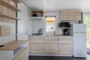 a kitchen with wooden cabinets and a white refrigerator at Mobil-home in Angles