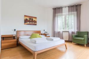 a bedroom with a bed and a green chair at appartamento casa stefi n1 in Malcesine +17 photos