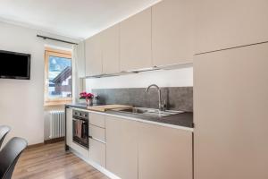 a kitchen with white cabinets and a sink at Condominio Lucia 7 Pinzolo in Pinzolo