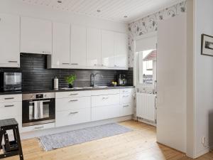 a white kitchen with white cabinets and black appliances at Apartment Alegränd by Interhome in Falkenberg +19 photos