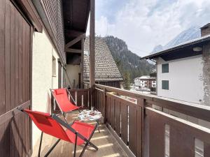 two red chairs sitting on the balcony of a house at Apartment Marmolada-13 by Interhome in Alba di Canazei