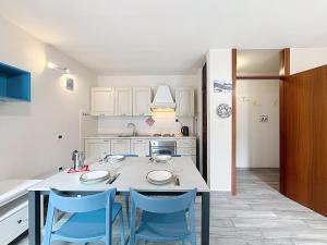 a kitchen with a table and blue chairs at Apartment Marmolada-13 by Interhome in Alba di Canazei +39 photos