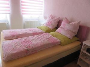 two beds with pink and yellow pillows in a bedroom at Ferienwohnung Sternenhof in Breisach am Rhein