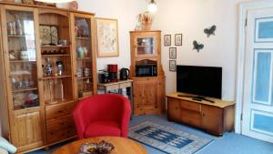 a living room with a tv and a red chair at Ferienwohnung Sternenhof in Breisach am Rhein