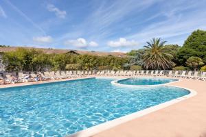 a swimming pool with chairs and people sitting in chairs at Appartement Bisbau in Moliets-et-Maa