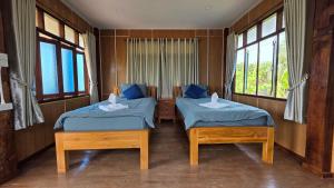 two twin beds in a room with windows at ฮักจังโฮมสเตย์ ที่พักแม่แตง in Chiang Mai