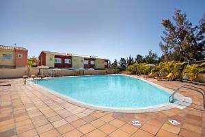 a large swimming pool with chairs and a building at Las Velas 37 in Meloneras