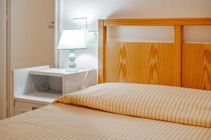 a bedroom with a bed with a wooden headboard and a lamp at La Capannuccia D in Ansedónia