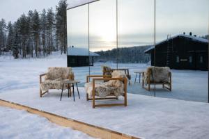 a group of chairs and tables in the snow at Sonka Resort Mirror House with Lake View in Rovaniemi
