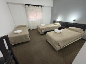 a hospital room with three beds and a window at HOTEL APOLO NEUQUEN in Neuquén