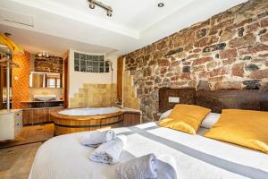a bedroom with a large bed and a stone wall at Aguas del Sella - jacuzzi in Precendi