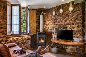 a stone walled living room with a tv and a fireplace at Aguas del Sella - jacuzzi in Precendi