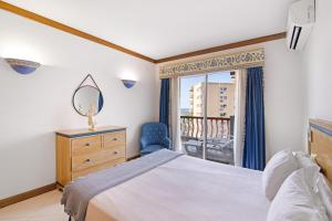 a bedroom with a bed and a mirror and a window at T2 com piscina centro Vilamoura in Vilamoura +17 photos