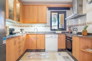 a kitchen with wooden cabinets and a white dishwasher at Ca Na Kika in Alcudia +13 photos