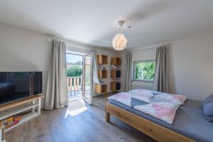 a bedroom with a bed and a television and a balcony at Ferienwohnung Selina in Taching am See