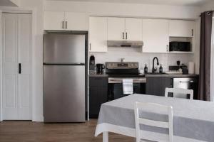a kitchen with white cabinets and a stainless steel refrigerator at Appart'hôtel Vivéo - Par Aneyro in Quebec City