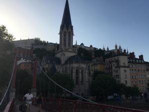 a group of people walking across a suspension bridge with a church at Maison St Ringo cozy apartment in Lyon +6 photos