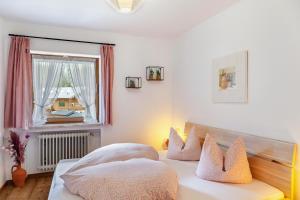 a bedroom with a bed with pillows and a window at Aschaubichl - Wohnung Alpenrose in Grainau