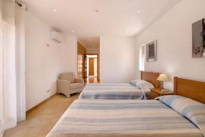 a room with three beds and a chair at Casa Tulipas in Loulé