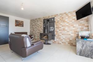 a living room with a leather chair and a fireplace at Maison de vacances Chez André in Meslan