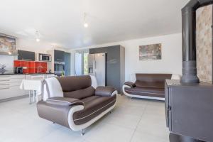 a living room with two leather couches and a stove at Maison de vacances Chez André in Meslan