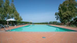 a large swimming pool with chairs and an umbrella at Appartamento Giglio in Riotorto