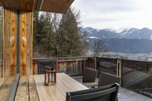 a wooden table and chairs on a balcony with mountains at Bei Kompis in Jenbach