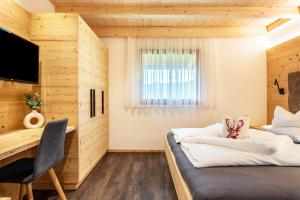 two beds in a room with a desk and a television at Zu Grof Morgenrot in Castelrotto