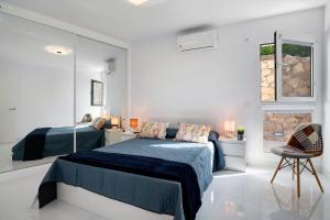 a white bedroom with a bed and a chair at Kay 4 in La Santa