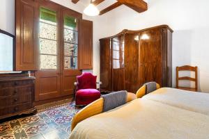 a bedroom with a bed and a red chair at Ca Cedó in Serra de Almós