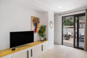 a living room with a flat screen tv on a white wall at Dreaming Penthouse Mogan in Mogán