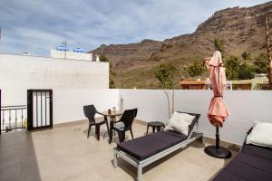 a balcony with a table and chairs and a mountain at Dreaming Penthouse Mogan in Mogán