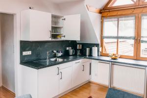 a kitchen with white cabinets and a sink and a window at Ferienwohnung Alte Schneiderei in Heideck
