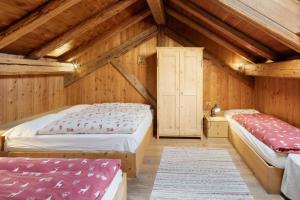 two beds in a room with wooden walls at Chalet El Deroch - Bellamonte in Bellamonte