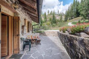 a patio with a table and a chair outside of a building at Chalet El Deroch - Bellamonte in Bellamonte