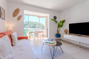 a living room with a couch and a tv and a table at Azur et Lavande proche plage in Fréjus