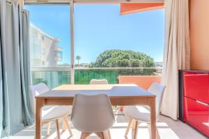 a dining room with a table and chairs and a large window at Azur et Lavande proche plage in Fréjus