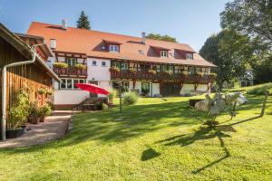 a large building with a red umbrella in a yard at Ferienwohnung Risthof 1 in Owingen