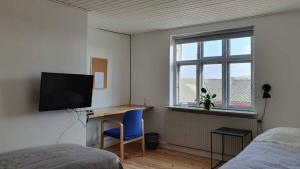 a bedroom with a desk and a television and a bed at Hyllemose Guesthouse in Lille Skensved