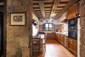 a kitchen with wooden cabinets and a stone wall at Casa Farigola in El Bruc