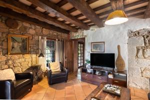 a living room with a tv and a stone wall at Casa Farigola in El Bruc