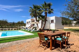 a wooden table and chairs next to a swimming pool at Villa Prats Ibiza in Sant Josep