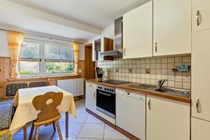 a kitchen with white cabinets and a table and a sink at Brumichelhof in Bad Peterstal-Griesbach