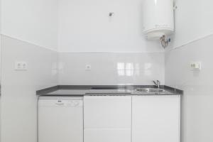 a kitchen with white cabinets and a sink at Casa Pepa in Barbate