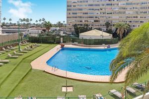 a large swimming pool with chairs and a large building at Los Molinos 202 in Maspalomas