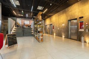 a lobby with a staircase and a sign on the floor at APS - Alpha Stay By Anora Spaces in Barueri
