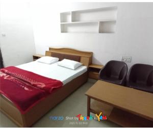 a bedroom with a bed and a desk and two chairs at Hotel prayag with ev car station 7,4kw in Nāthdwāra +1 photo