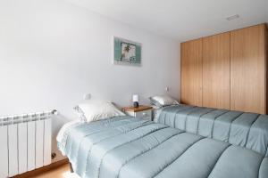 a bedroom with two beds with blue sheets at Apartamento Bali com Piscina in Apúlia +13 photos